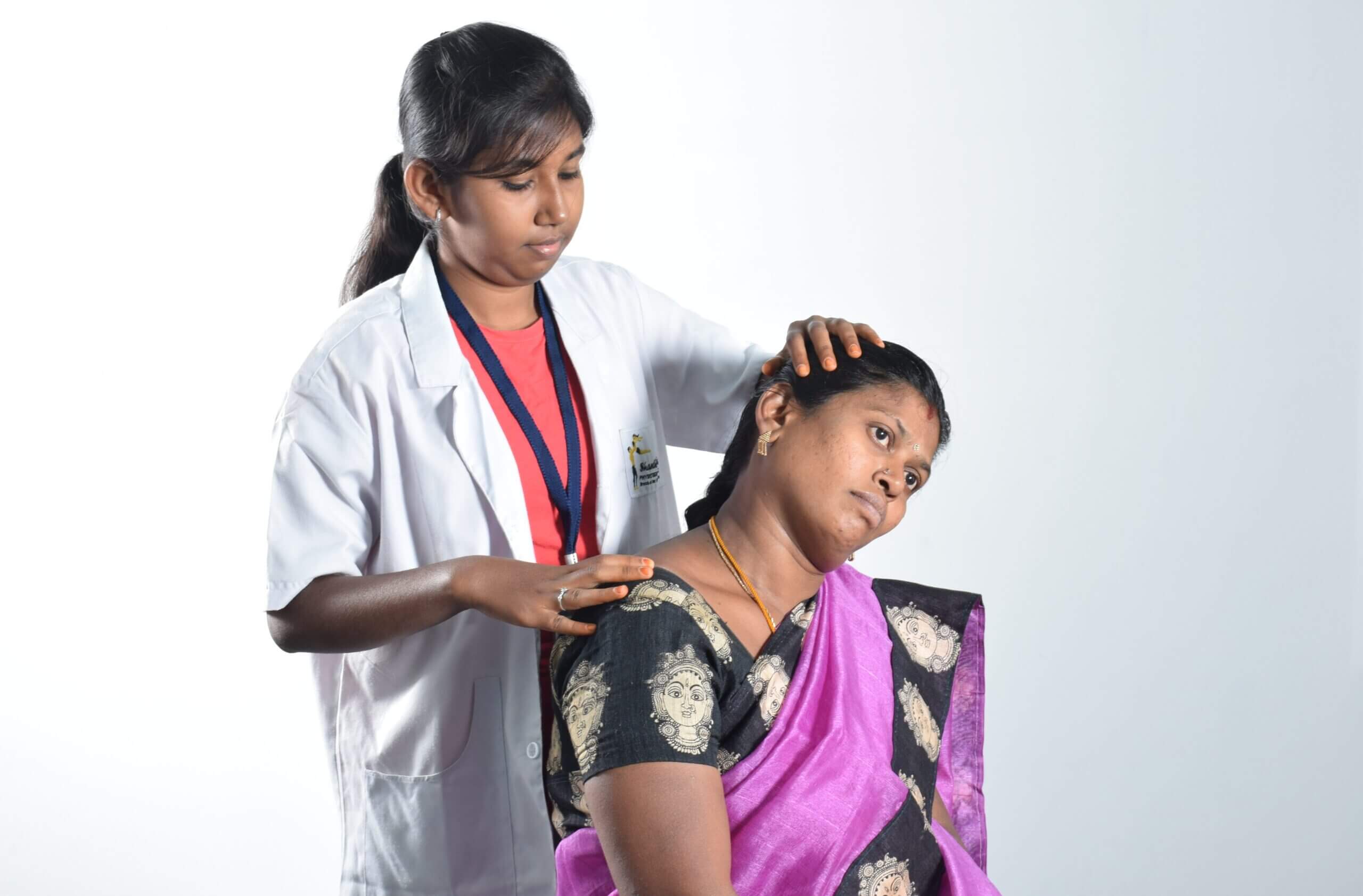 A physiotherapist in a white coat gently performs a neck therapy session on a patient