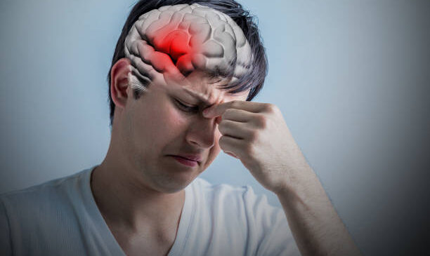 Person holding forehead in pain, eyes closed