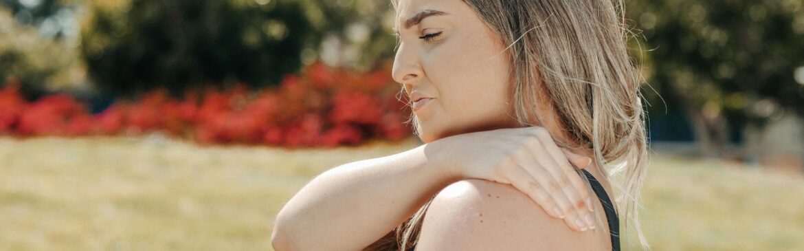 A woman is seen holding her shoulder, displaying signs of pain and distress.