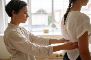 A woman is giving a massage to another woman, promoting relaxation and therapeutic benefits in a calm setting