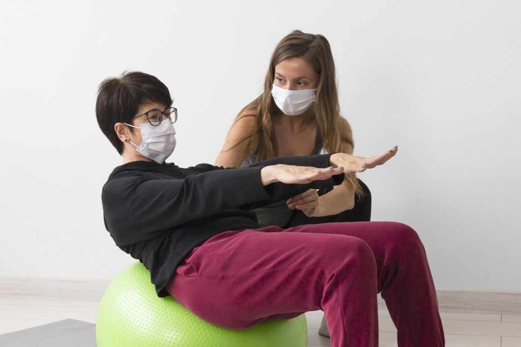 Woman training fitness ball while wearing medical mask